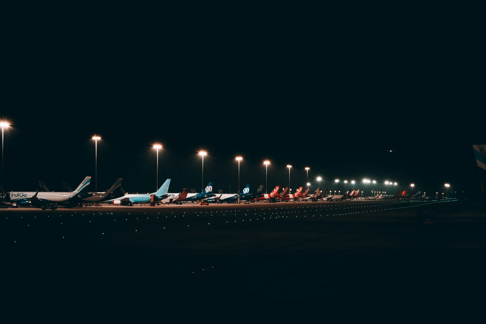 Apron de aeropuerto de noche con aviones estacionados y luces ámbar